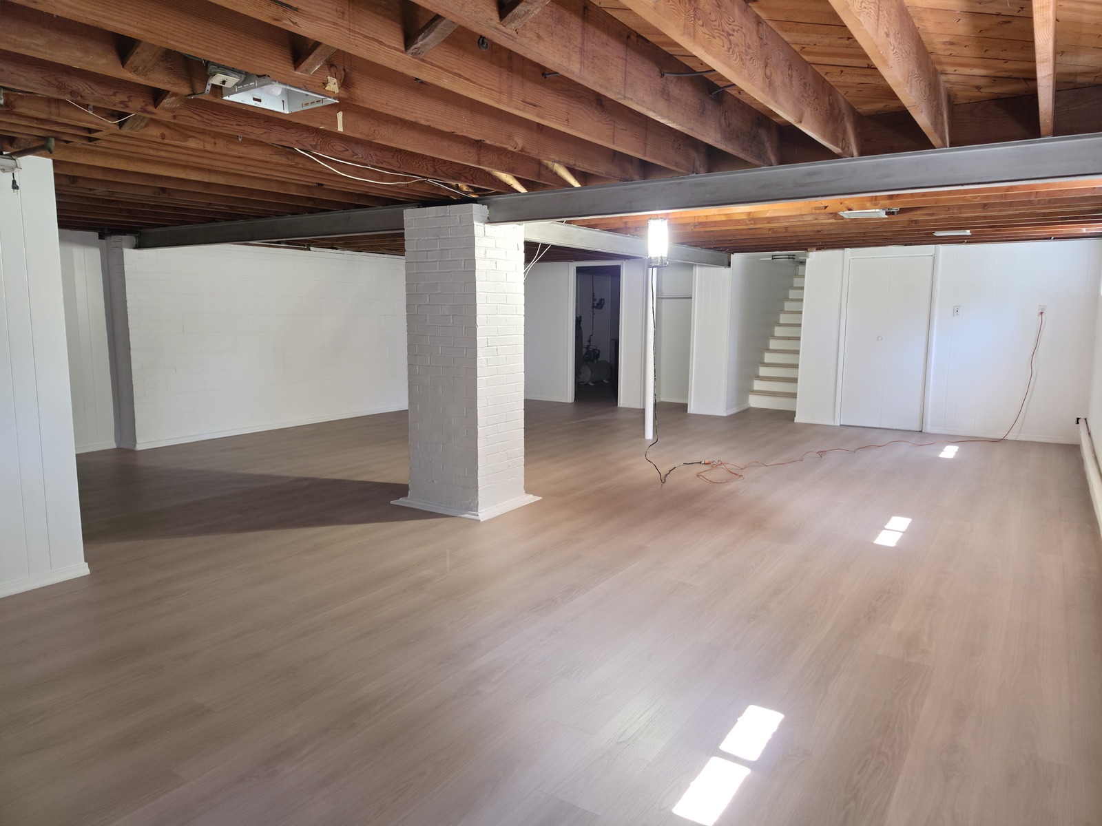 Basement with new LVP flooring and white masonry walls