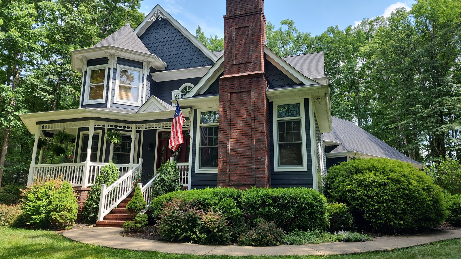 Blue house with white architectural trim and a brick chimney