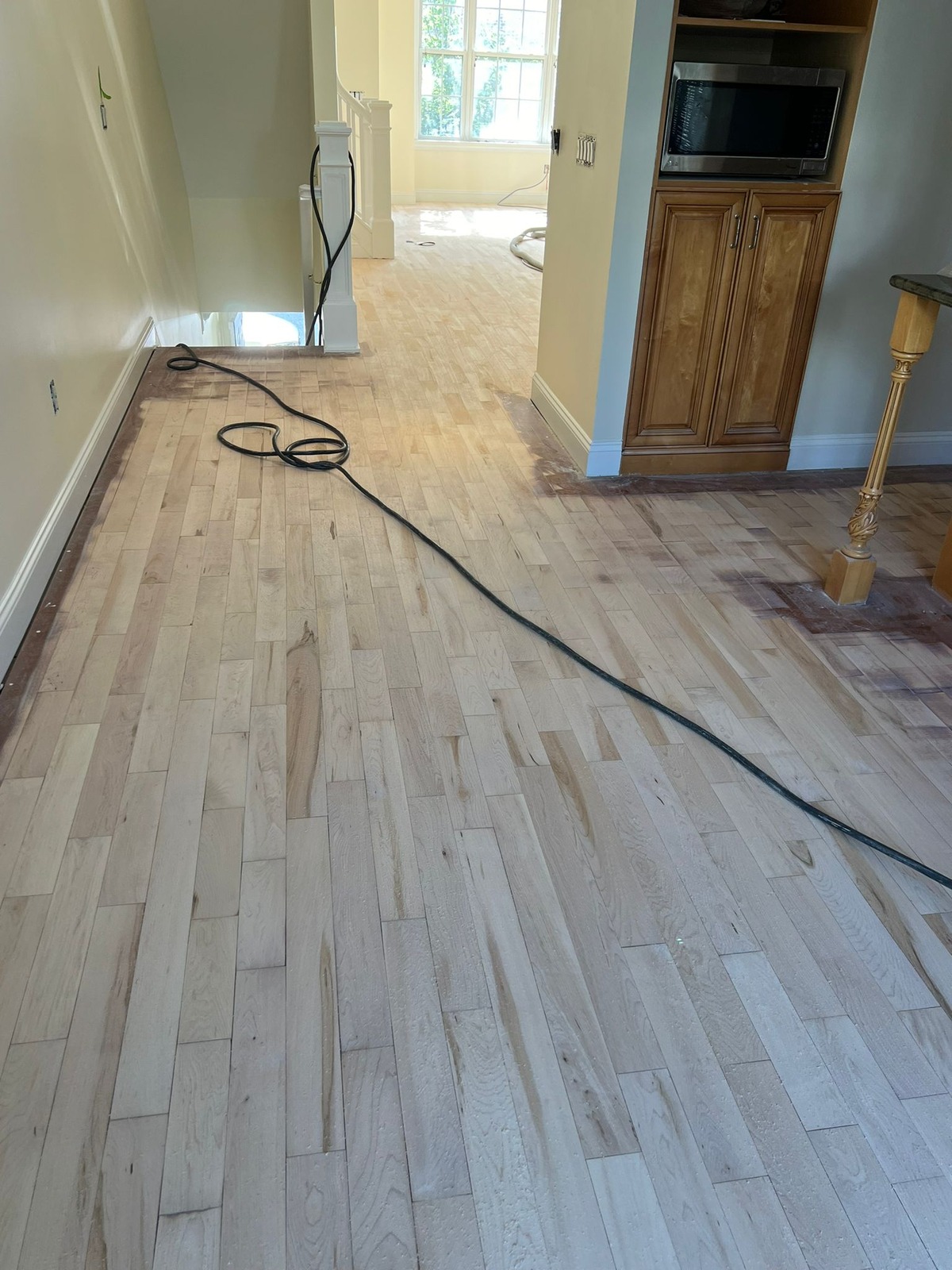Partially sanded wood floor with a darker unfinished perimeter