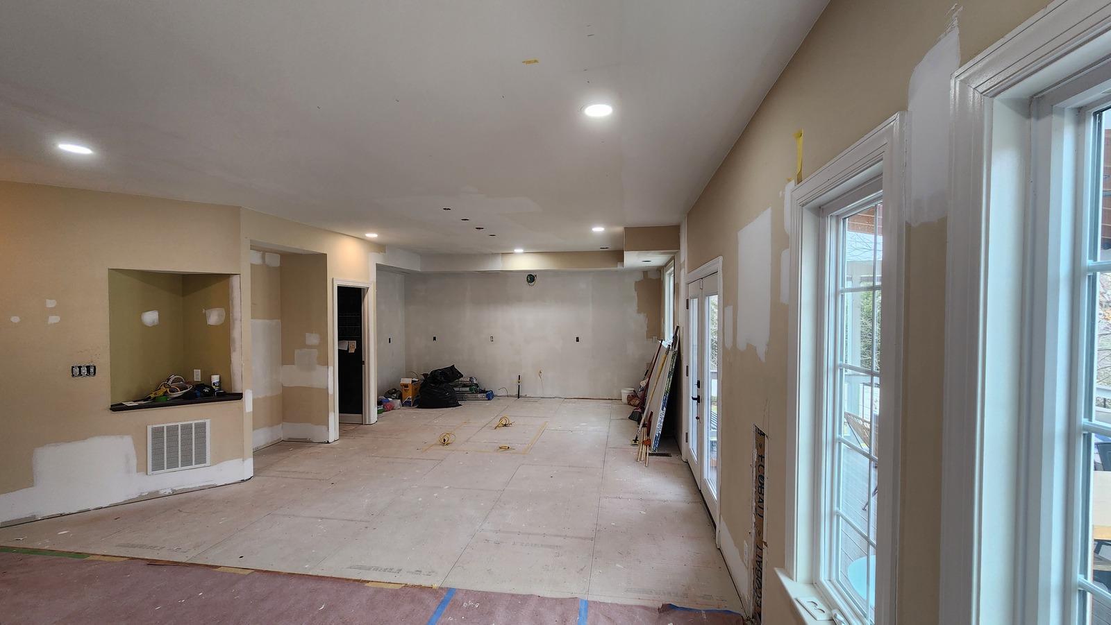 Patched walls and ceiling in a room with floor protection and work materials